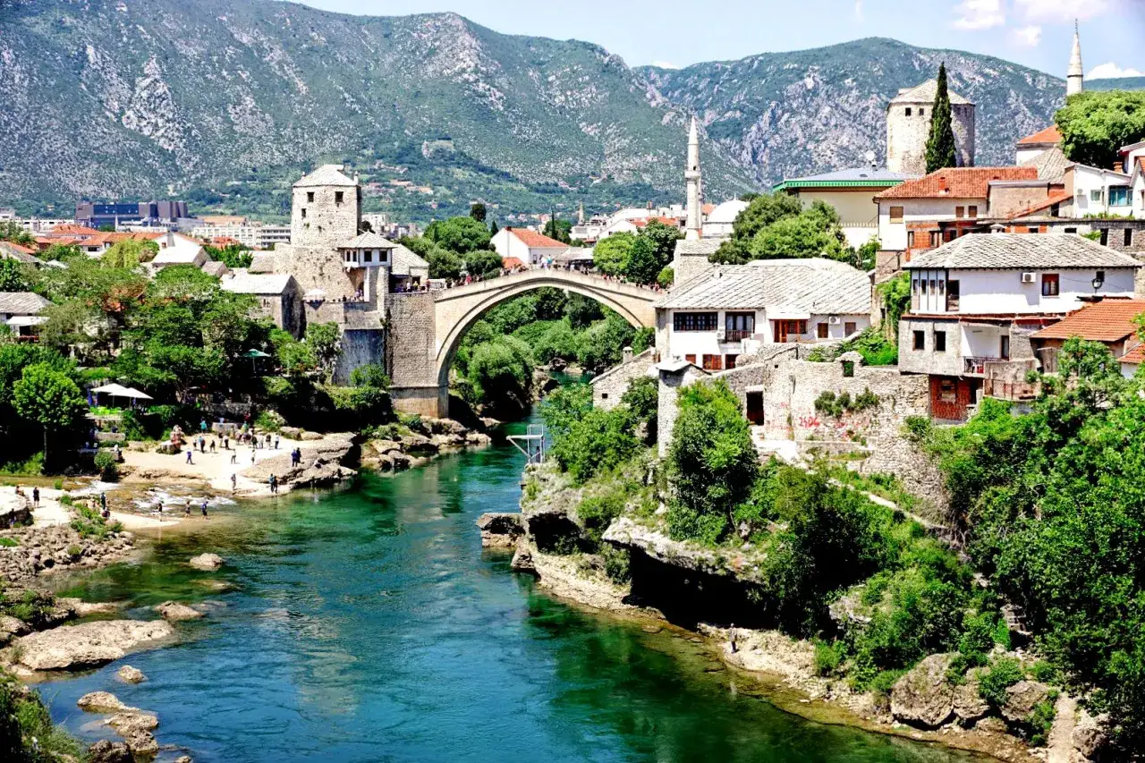 Mostar, Bośnia i Hercegowina: zielona karta dla turystów. Stary Most i rzeka Neretwa w letnim słońcu.