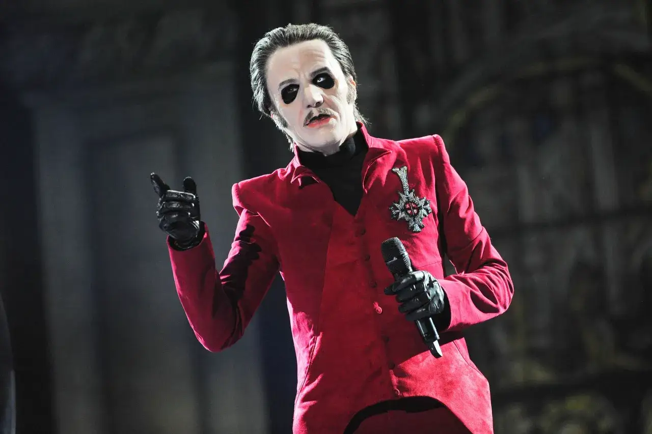 Kto to jest mim? To wokalista Ghost w czerwonym fraku, z makijażem i mikrofonem.