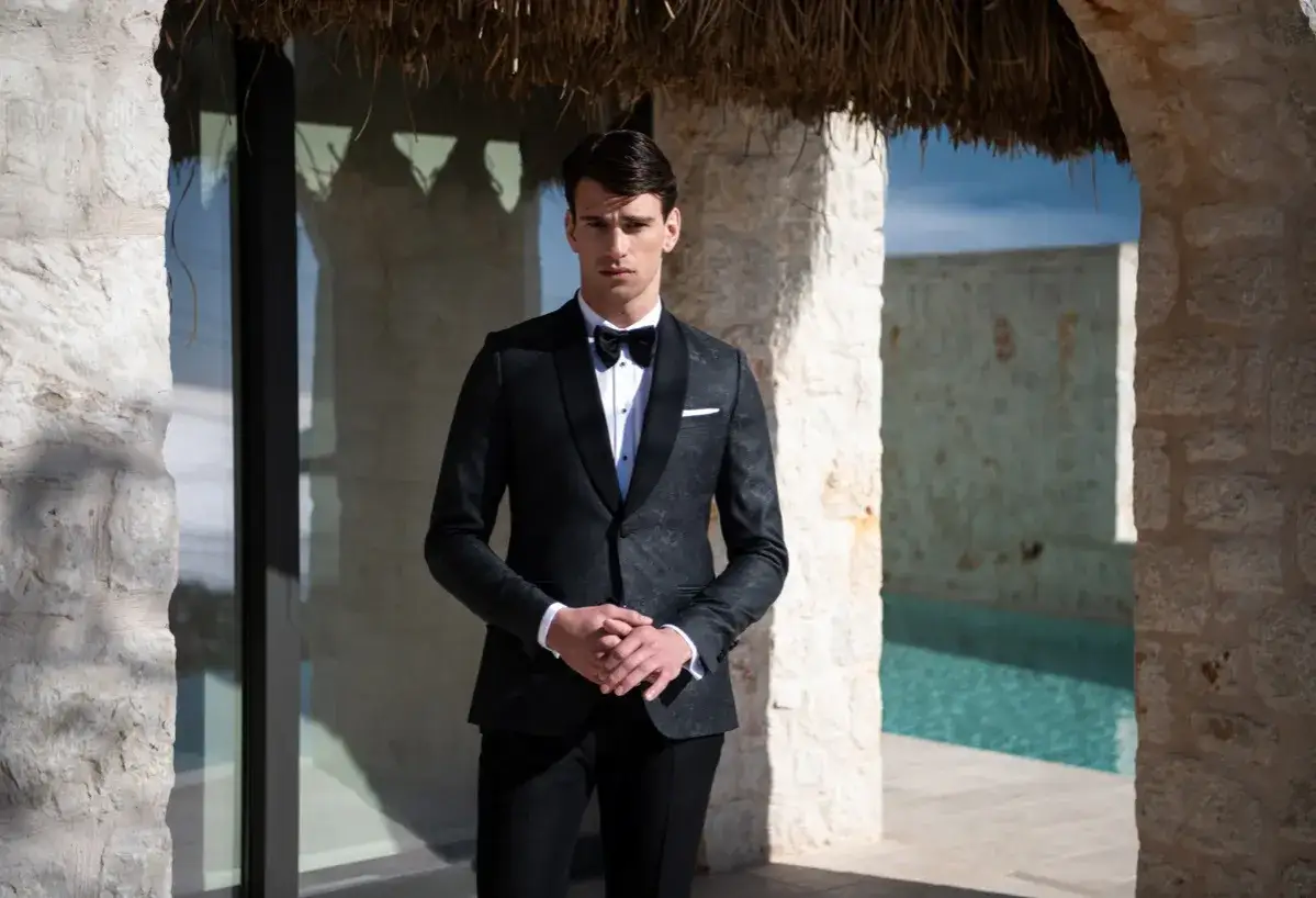 Elegancki mężczyzna w smokingu, idealny przykład stroju black tie na wesele. Różnica między ubiorem black tie a cocktail dress dla gości weselnych jest widoczna.