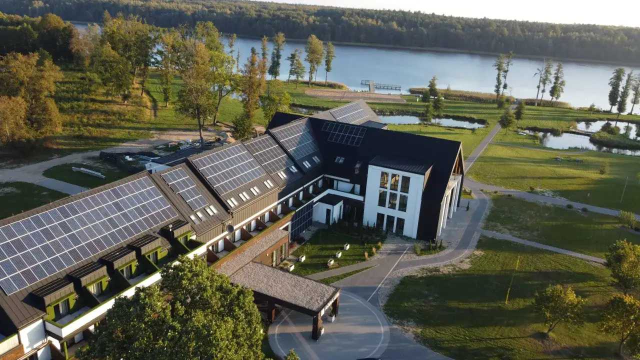 Nowoczesny hotel z panelami słonecznymi nad jeziorem, idealny na Mazury all inclusive.