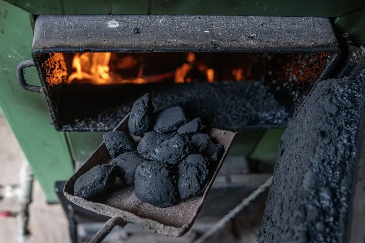 Łopata z węglem brunatnym czeka na załadunek do pieca bezklasowego, gdzie wesoło płonie ogień.
