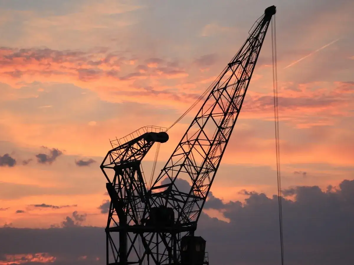 Sylwetka dźwigu na tle zachodzącego słońca. Ten resurs dźwigu, co to jest, to potężna konstrukcja gotowa do pracy.