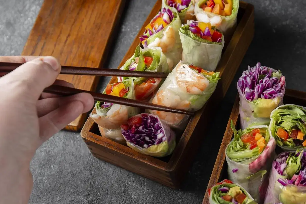 Chwytam pałeczkami świeże sajgonki z krewetkami, czerwoną kapustą i warzywami. Idealne co do sushi!