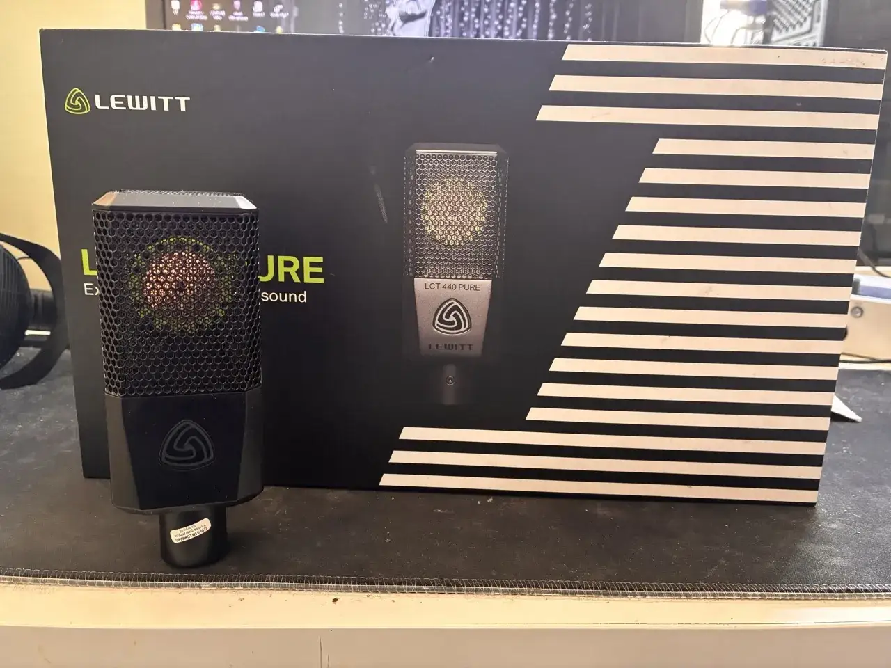 Mikrofon Lewitt LCT 440 PURE na tle czarnego pudełka z białymi paskami.