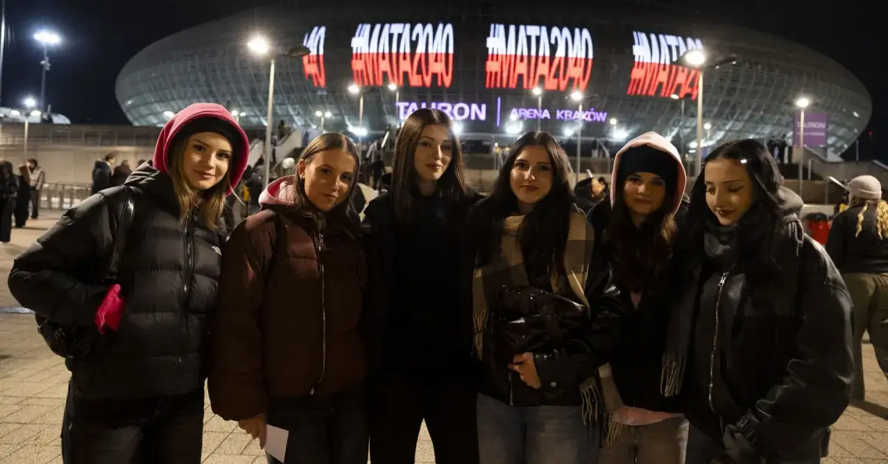 Grupa młodych kobiet czeka na koncert Maty w Krakowie. Na Tauron Arenie świeci napis #MATA2040.