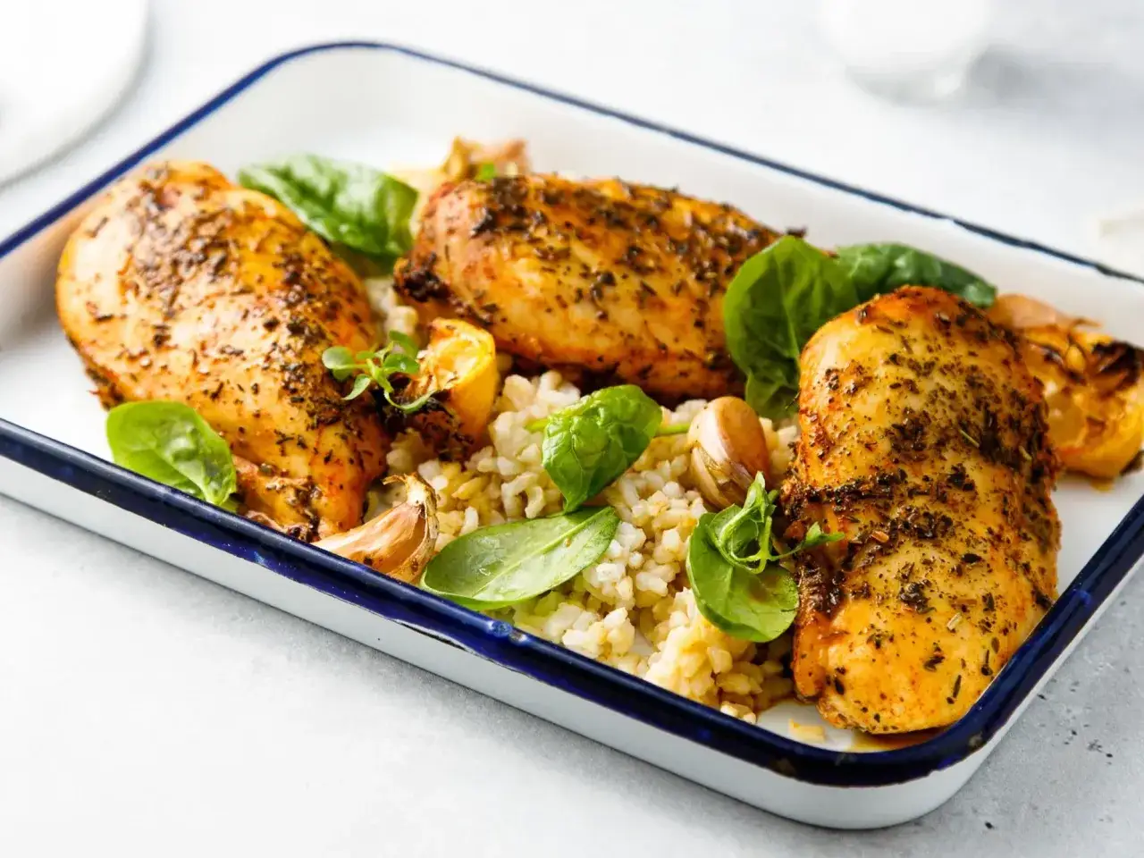 Pieczone piersi kurczaka z ryżem, czosnkiem, cytryną i szpinakiem w naczyniu.