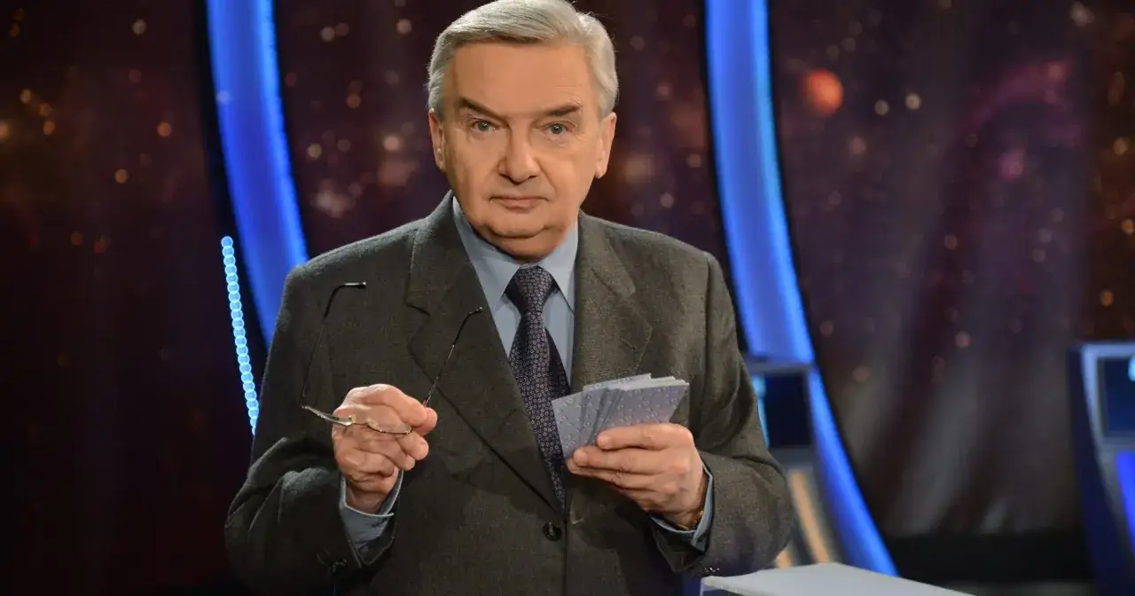 Starszy mężczyzna w garniturze trzyma okulary i karty z napisem "jeden z dziesięciu kiedy".