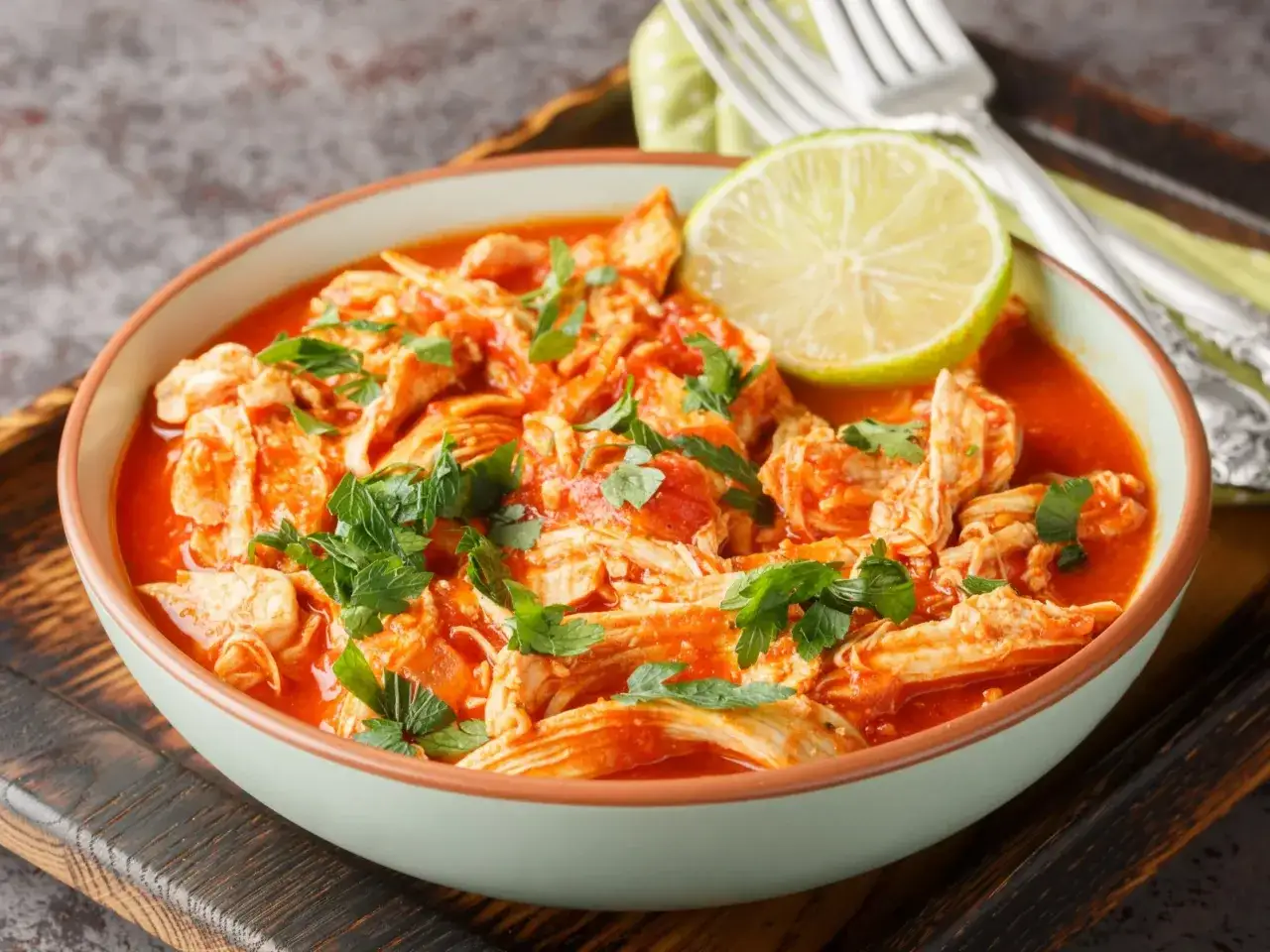 Pyszne danie z ugotowanych udek kurczaka w sosie pomidorowym, posypane natką pietruszki i udekorowane plasterkiem limonki. Idealne, gdy zastanawiasz się, co zrobić z ugotowanych udek kurczaka.