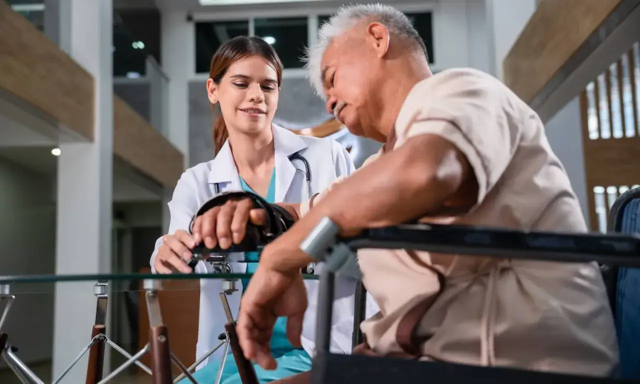 Fizjoterapeutka pomaga starszemu mężczyźnie w rehabilitacji ud. Ćwiczenia pomagają odzyskać sprawność po urazach.