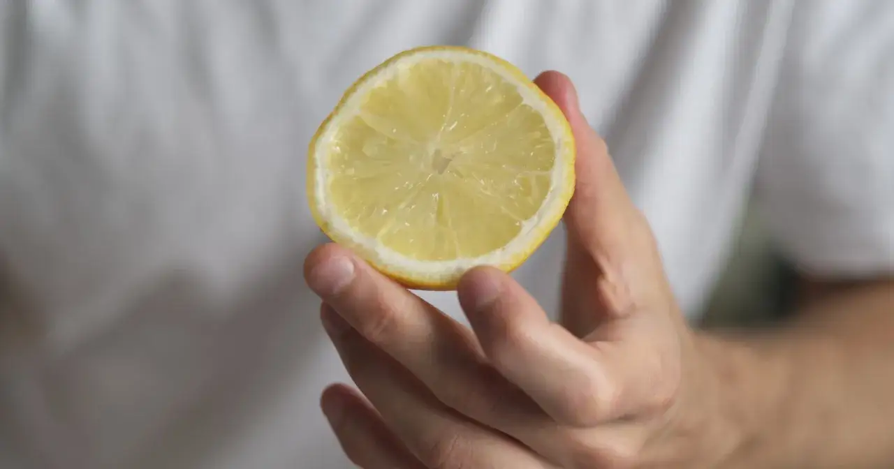 Dłoń trzyma plasterek cytryny. Zastanawiasz się, ile jeść mrożonej cytryny dla zdrowia?