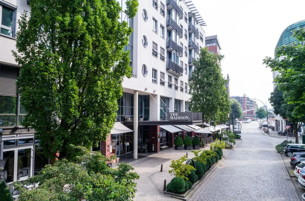 Das Madison Hotel Hamburg mit Außenbereich und Blick auf eine kopfsteingepflasterte Straße.