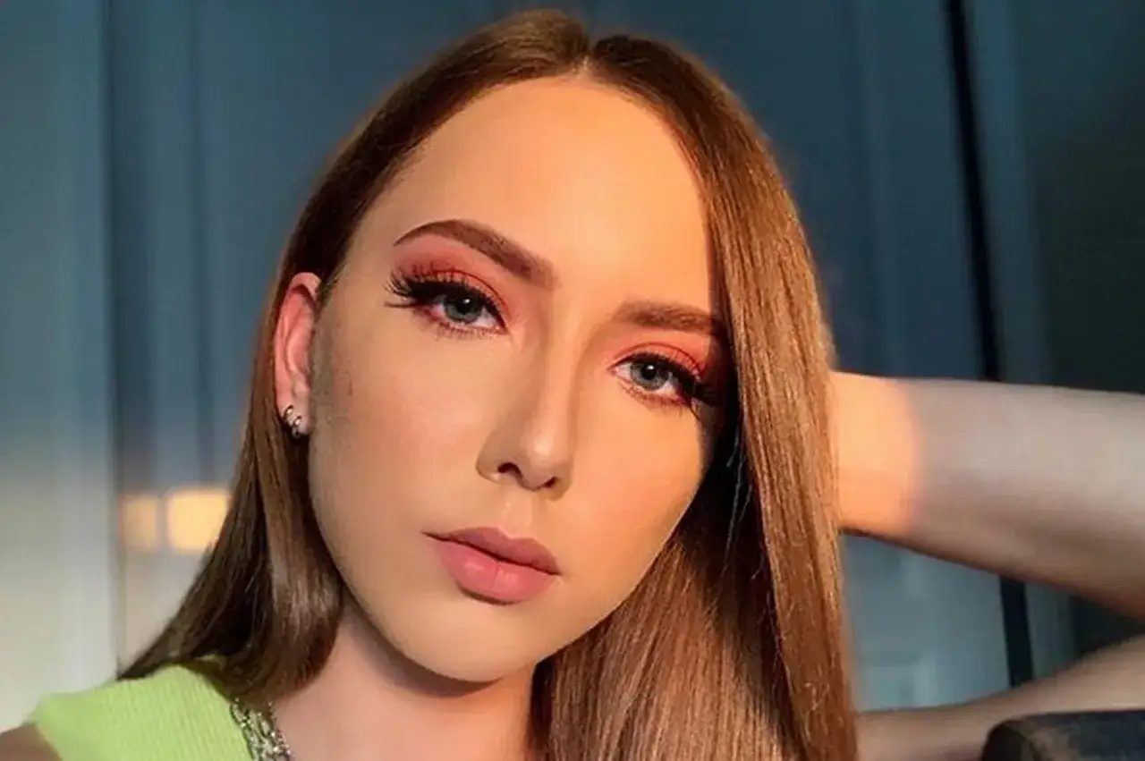 Młoda kobieta z makijażem oczu w kolorze koralowym i różowymi ustami.