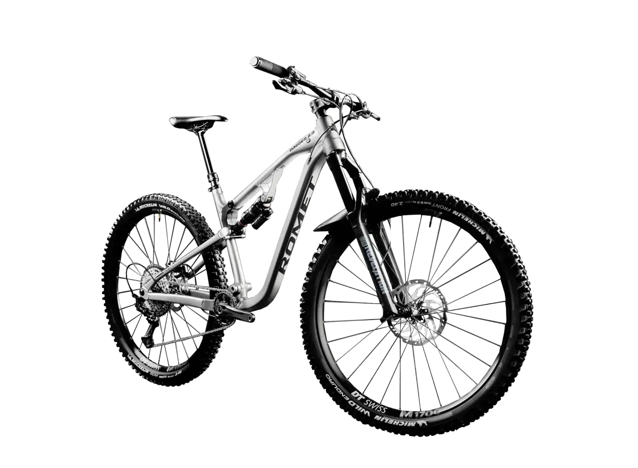 Srebrny rower górski (MTB) z pełnym zawieszeniem, szerokimi oponami Michelin Wild Enduro i amortyzatorem Rock Shox. Idealny na trudne trasy, nie crossowy.