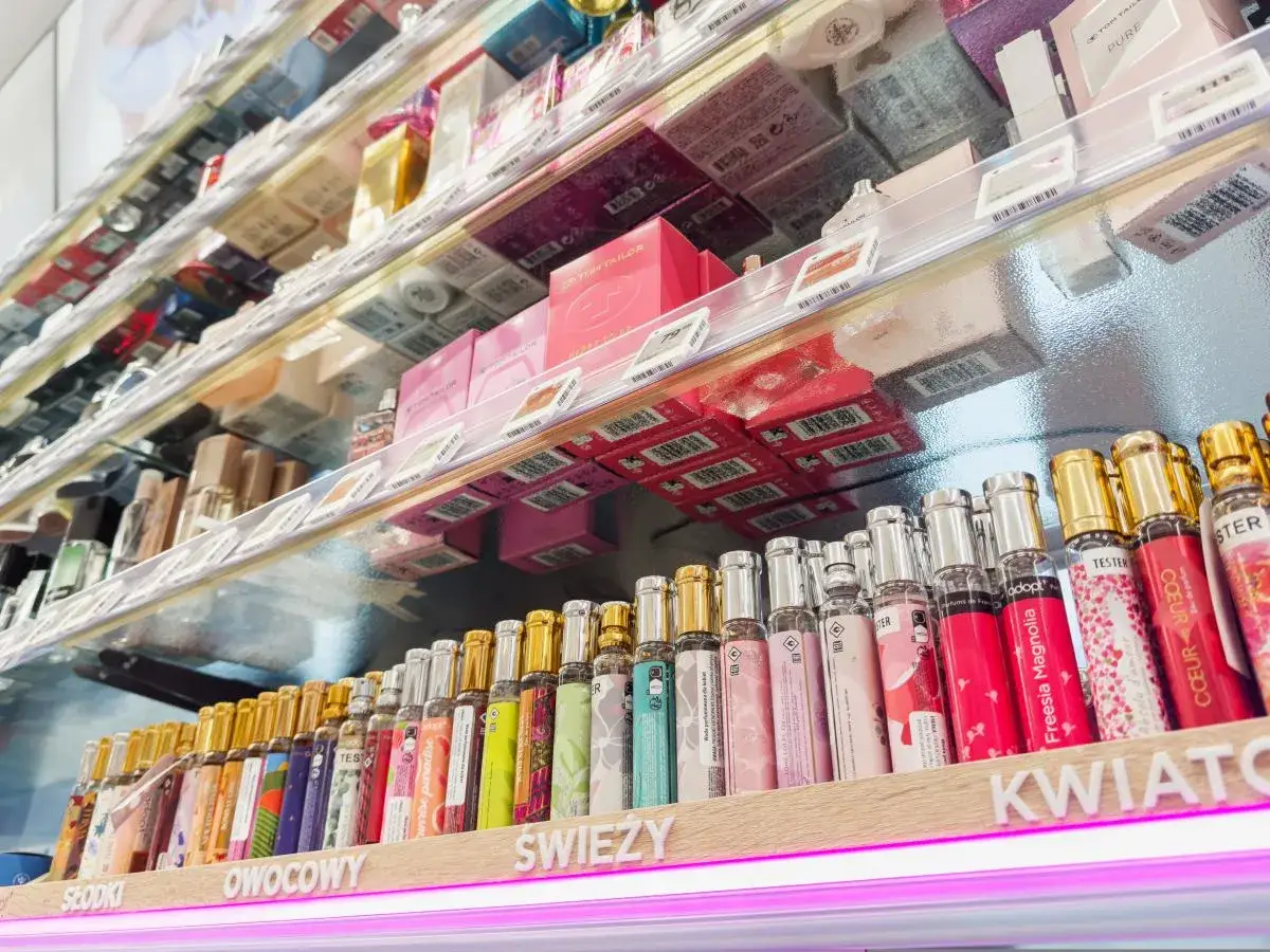 Rząd flakoników perfum na półce. Na etykietach widnieją nazwy i opisy, np. "Freesia Magnolia". Zastanawiasz się, ile ml ma jedno psiknięcie perfum?