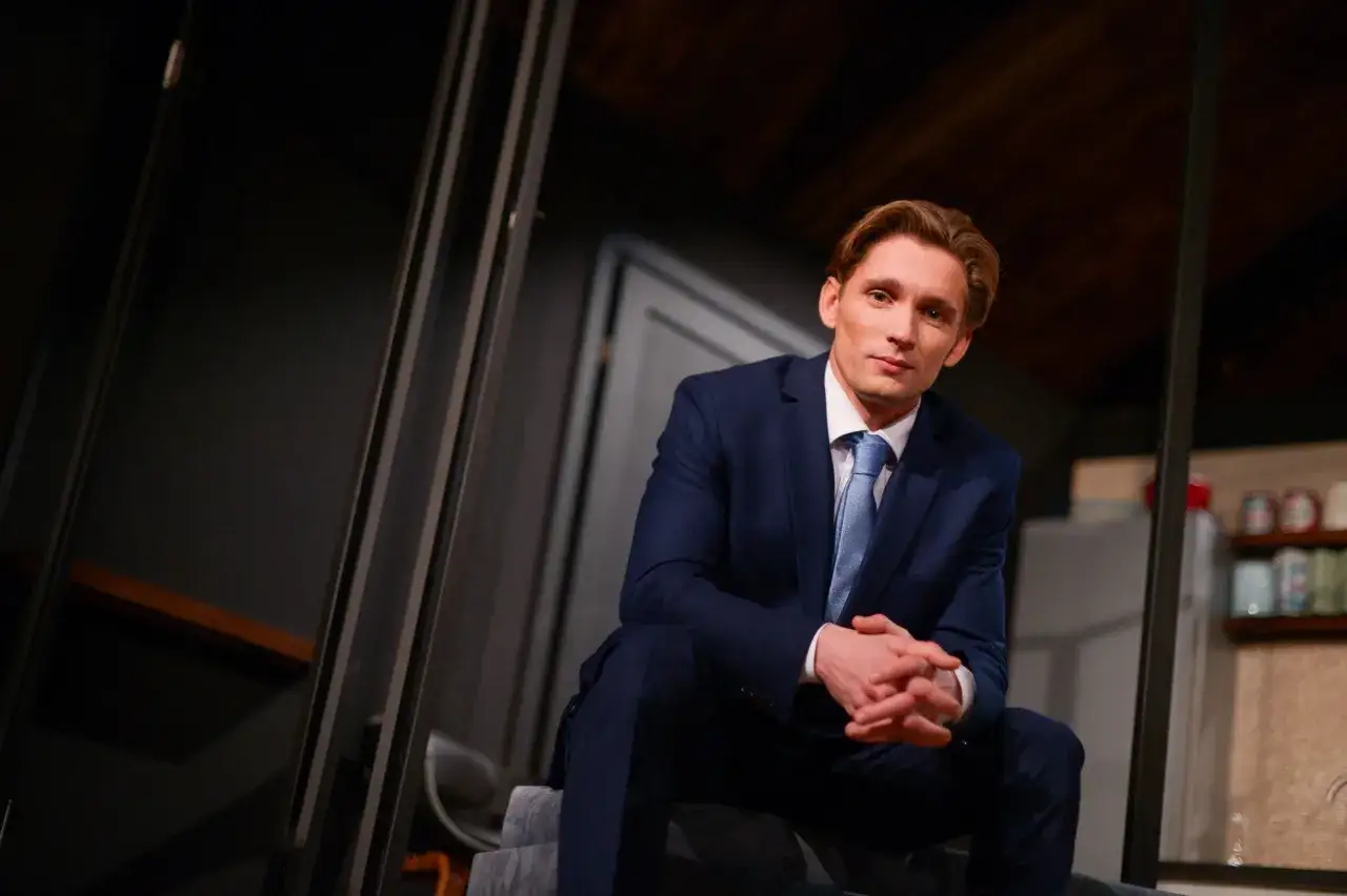 Filip Gurłacz w garniturze, siedzi na schodach, zastanawiając się, jaka to melodia.