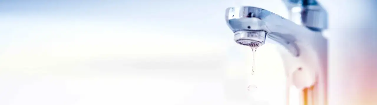 Kropla wody spadająca z chromowanego kranu.