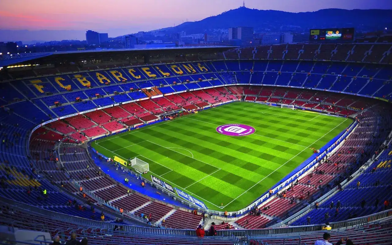 Camp Nou w Barcelonie, gdzie FC Barcelona gra w Lidze Mistrzów. Stadion w barwach klubu, z widokiem na miasto i wzgórza.