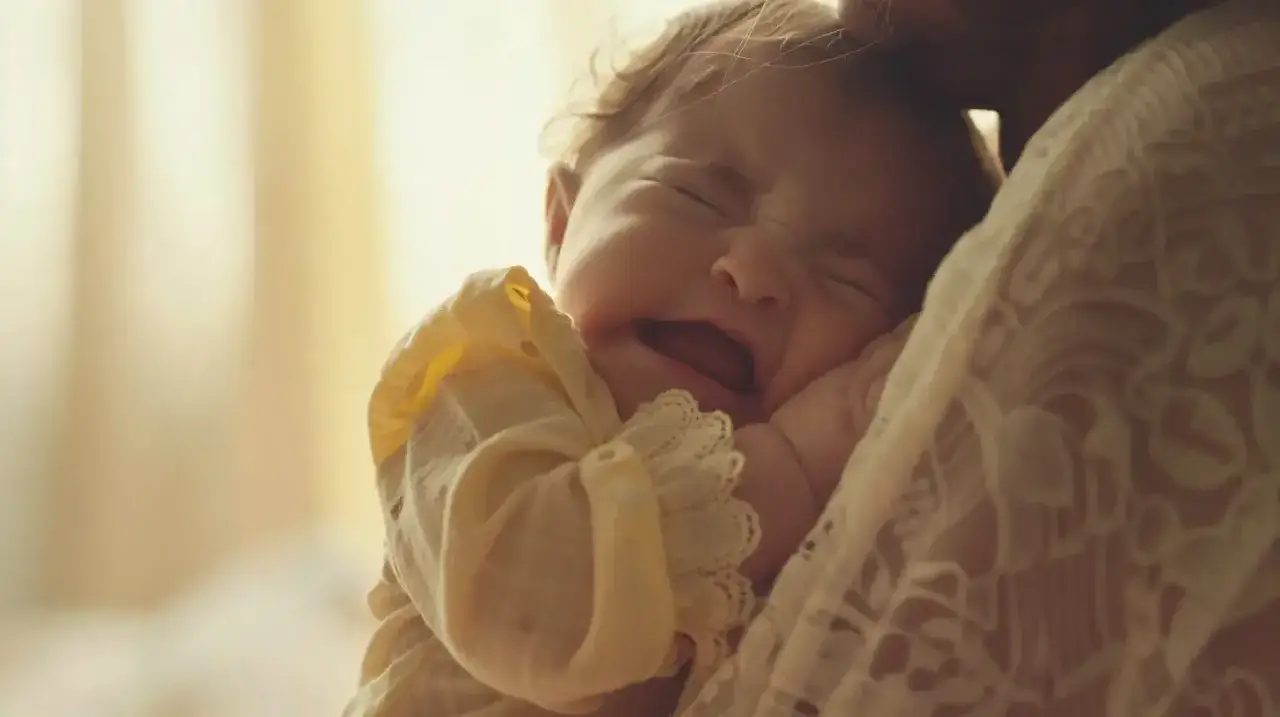 Malutkie dziecko płacze, tulone przez mamę. Ząbkowanie i biegunka to trudny czas dla malucha.