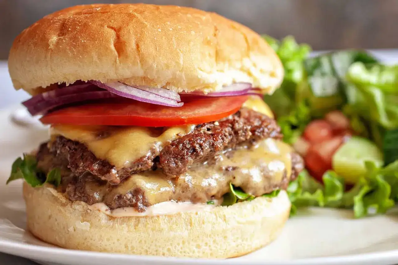 Soczysty burger wołowy z serem, pomidorem, cebulą i sałatką.