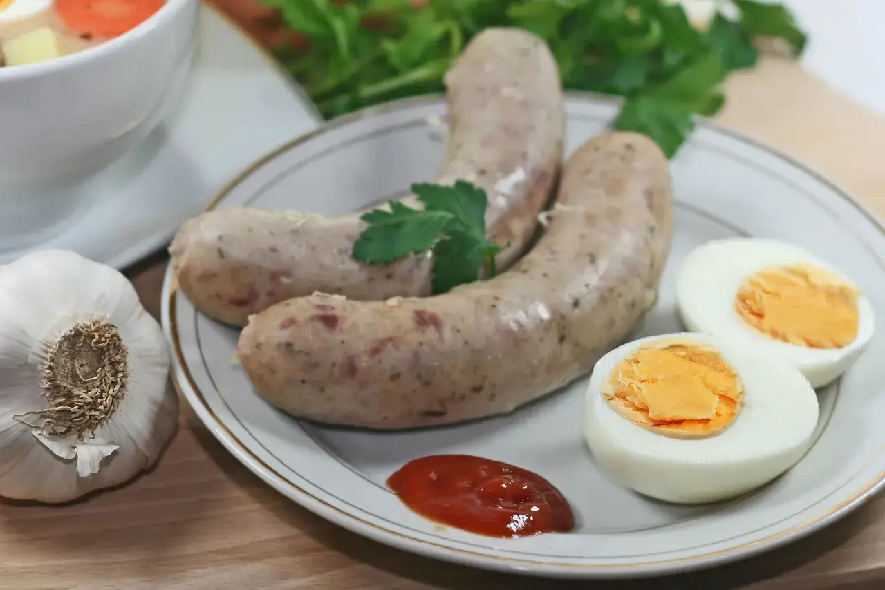 Biała kiełbasa z jajkiem i ketchupem, obok czosnek i natka. Idealne dodatki, jakie przyprawy do białej kiełbasy?