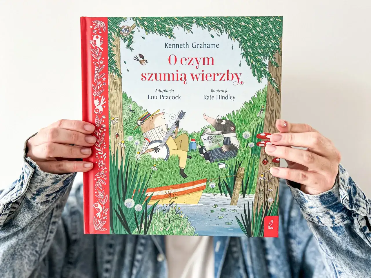 Okładka książki "O czym szumią wierzby" przedstawia zwierzątka nad rzeką. Kret czyta gazetę, a szczur gra na banjo.