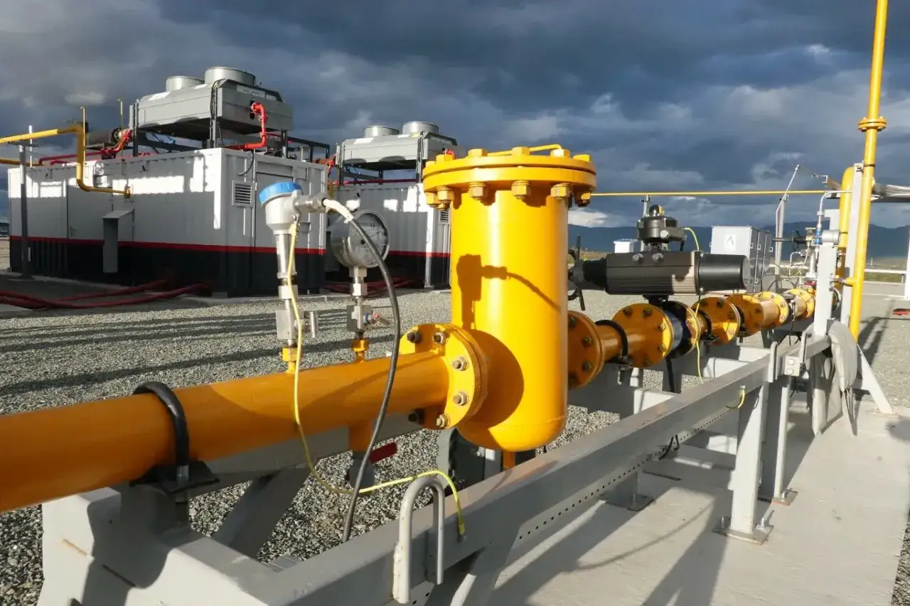 Żółte rury i zawory na tle budynków z chłodnicami, część infrastruktury dla elektrowni gazowych w Polsce.