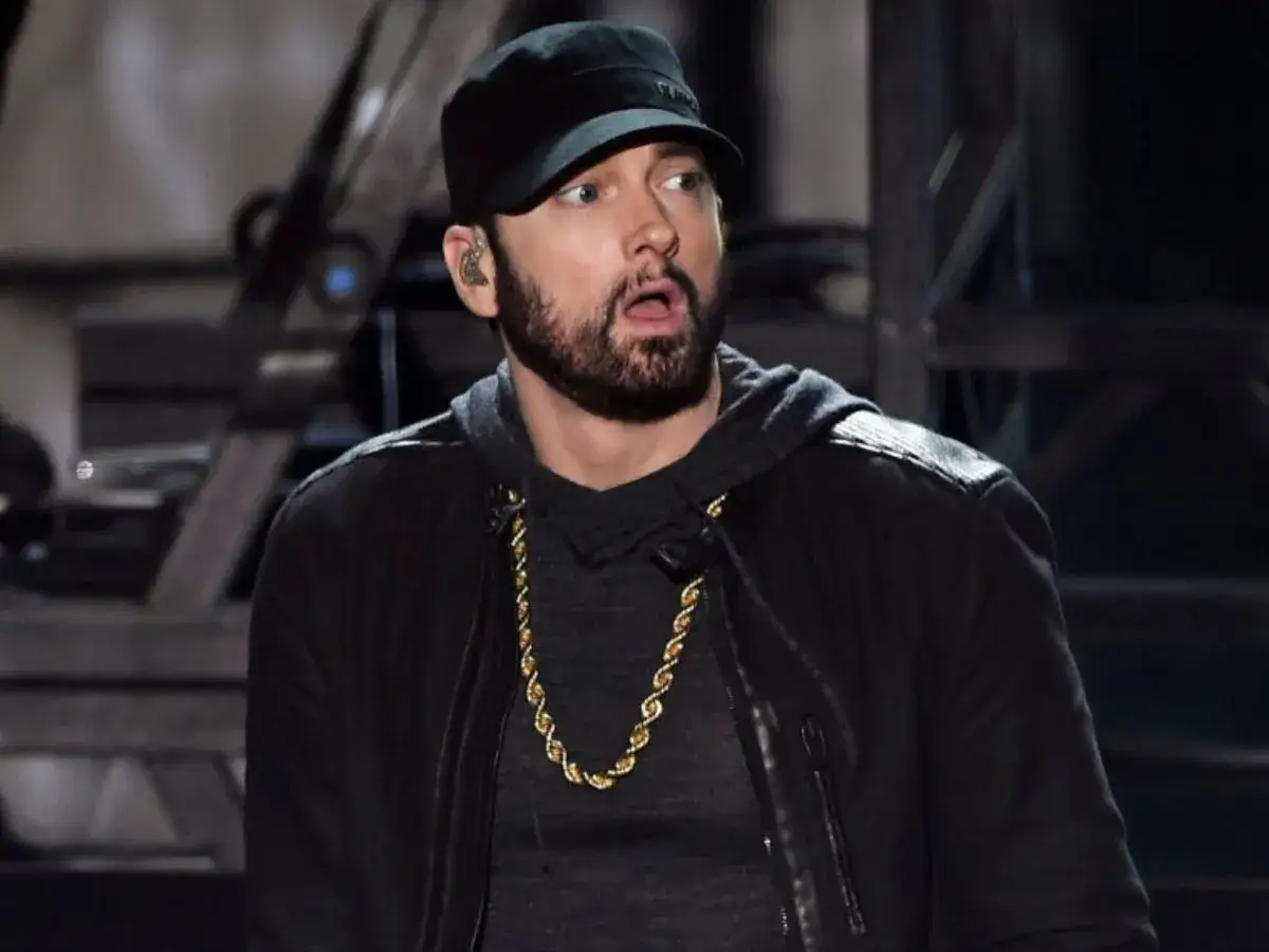 Eminem w czapce i złotej koli, z miną sugerującą zdziwienie, jakby usłyszał pytanie: czemu Eminem nie lubi Polski.