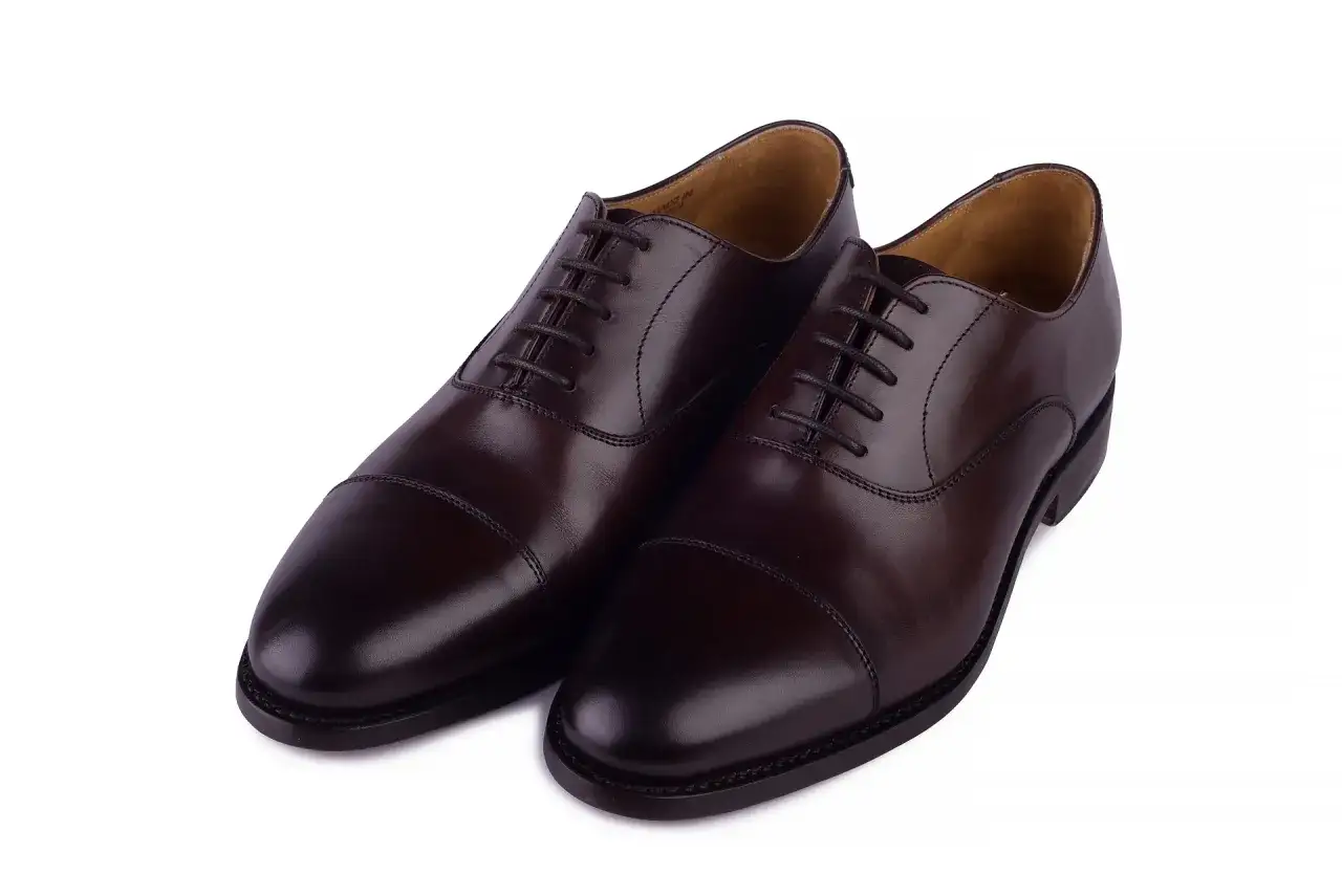 Eleganckie, brązowe buty angielskie marki, wykonane ze skóry, z klasycznym sznurowaniem i ozdobnym przeszyciem na nosku.