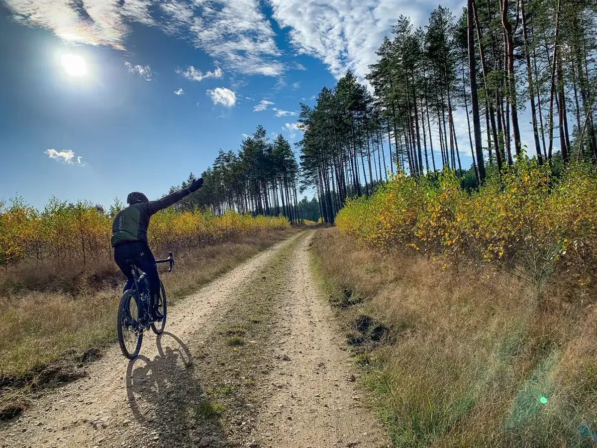 Rowerzysta na szutrowej drodze, cieszący się jesiennym krajobrazem. To prawdziwy gravel po łódzku, z dala od miejskiego zgiełku.