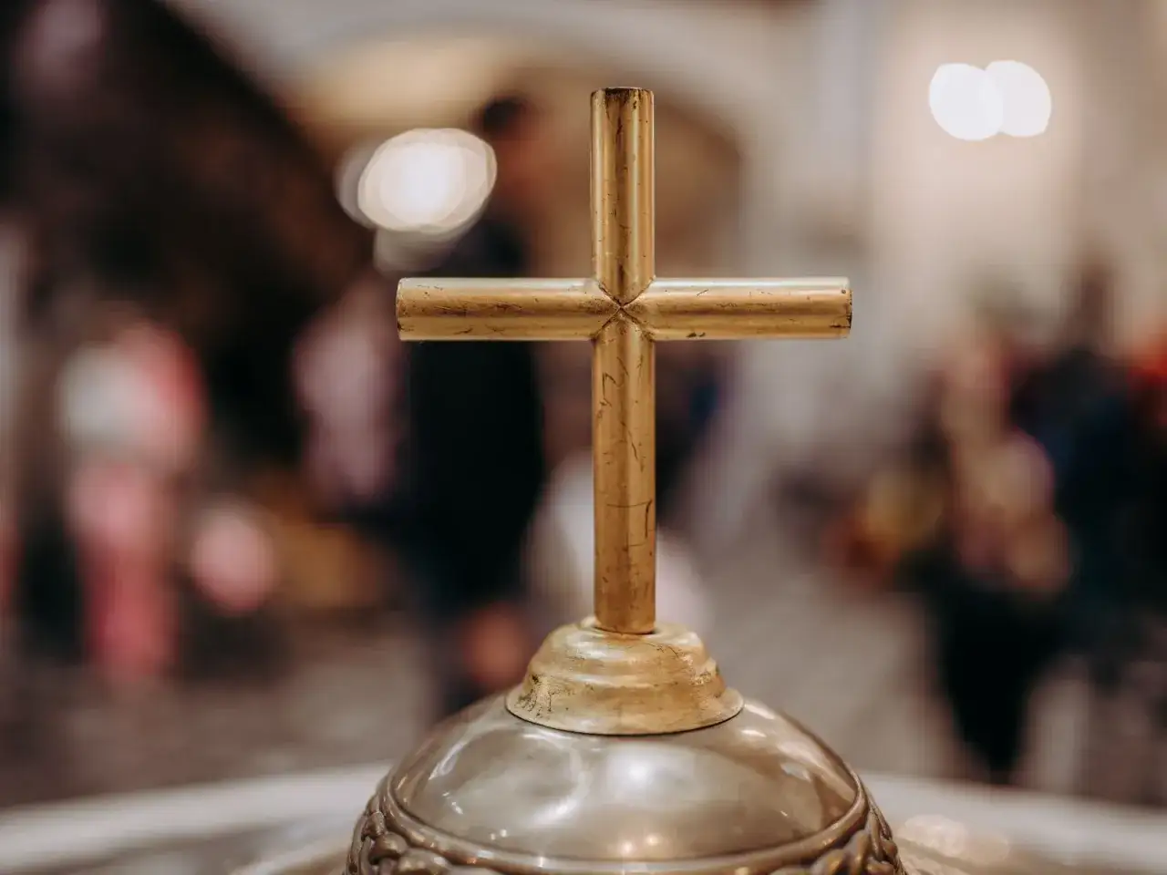 Złoty krzyż na ołtarzu, symbol wiary i 5 przykazań kościelnych. W tle rozmyte postacie wiernych.