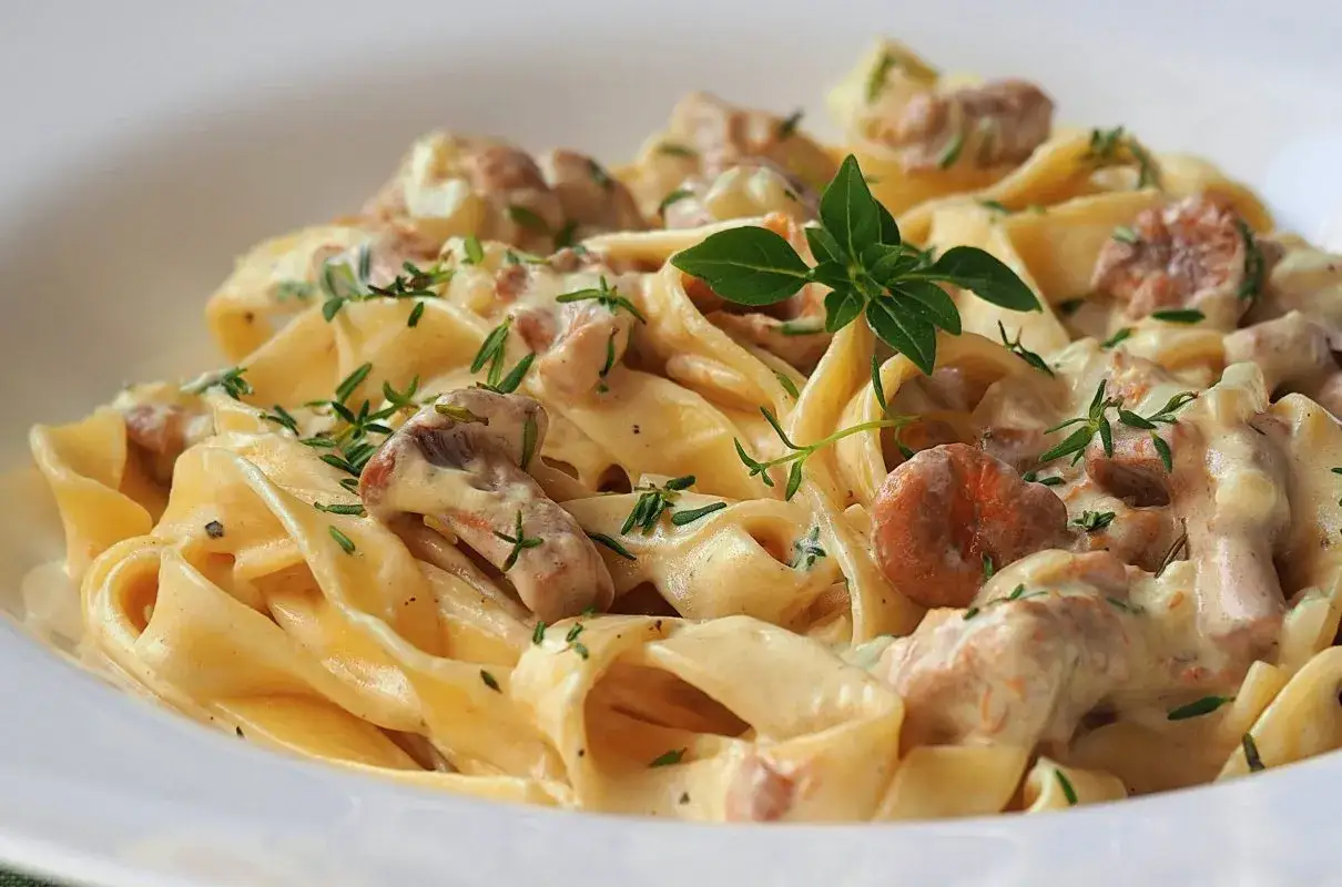 Pyszny makaron z kurkami w kremowym sosie, udekorowany świeżymi ziołami. Idealne danie dla miłośników grzybów.