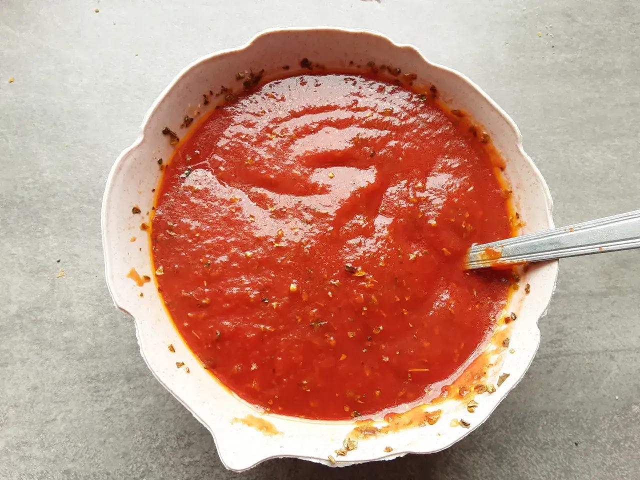 Domowy sos do pizzy, gęsty i aromatyczny, z ziołami w misce. Idealny na każdą okazję.