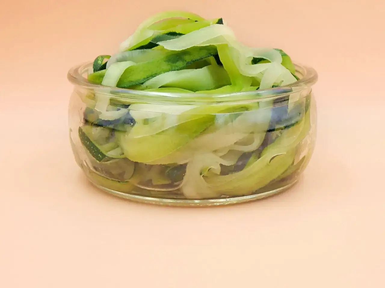 Szklany słoik wypełniony świeżym, zielonym makaronem z cukinii, gotowym do przygotowania zdrowego posiłku.