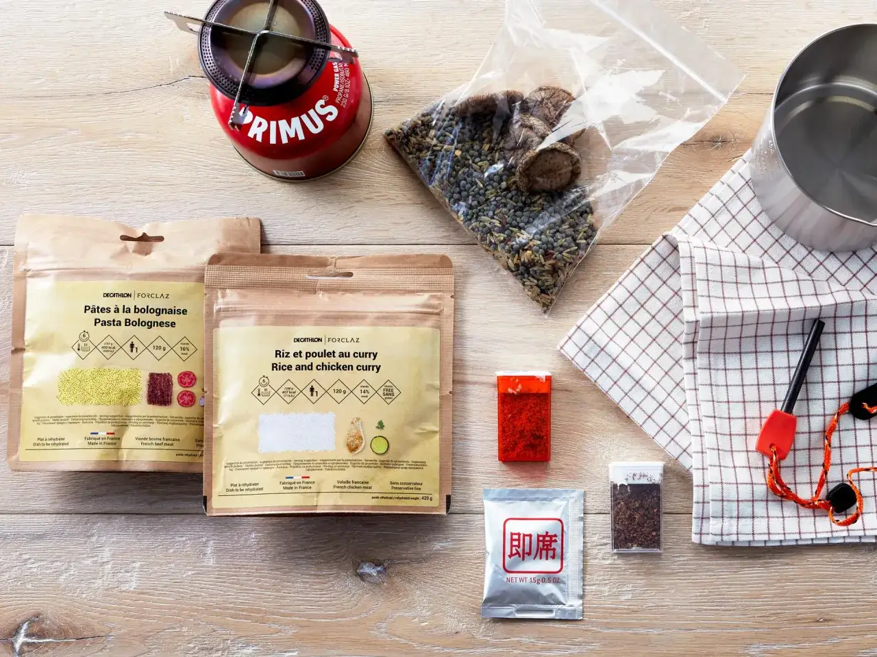 Zestaw żywności liofilizowanej na górską wyprawę: makaron bolognese, curry z kurczakiem, przyprawy, kuchenka turystyczna.