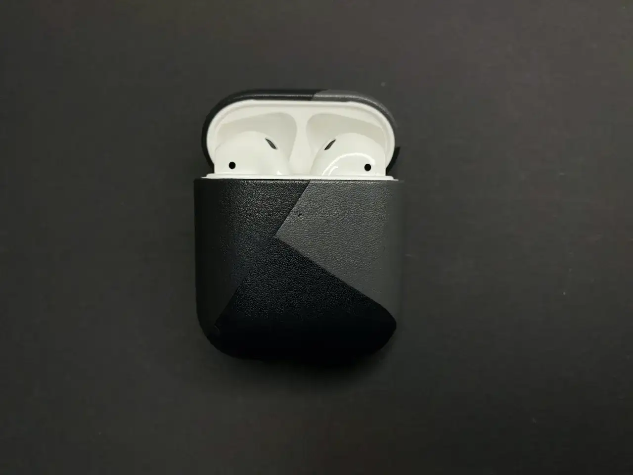 AirPods in einer schwarzen Hülle mit grauem geometrischem Muster.