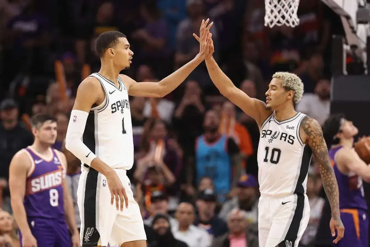 Dwóch koszykarzy San Antonio Spurs świętuje udaną akcję, która zakończyła się asystą w koszykówce.