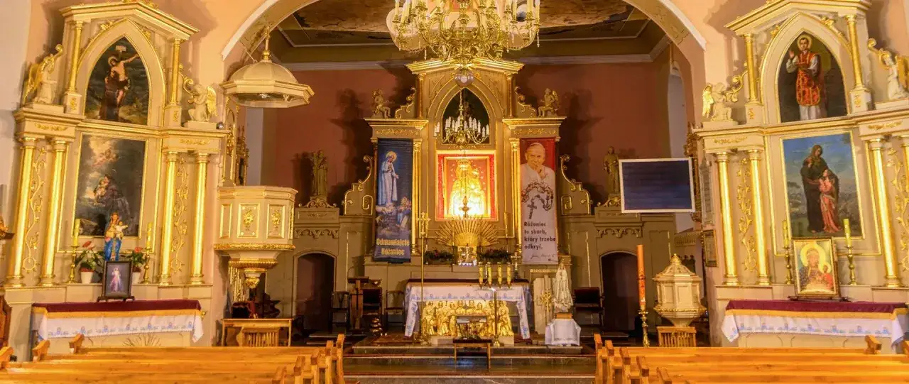 Ołtarz główny kościoła z obrazami świętych i portretem Jana Pawła II.