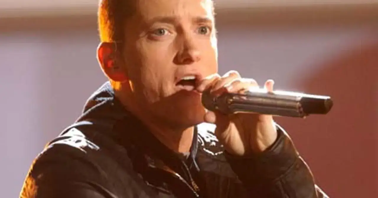 Eminem śpiewa do mikrofonu. Choć jego wzrost, czyli ile Eminem ma wzrostu, nie jest widoczny, jego energia na scenie jest ogromna.