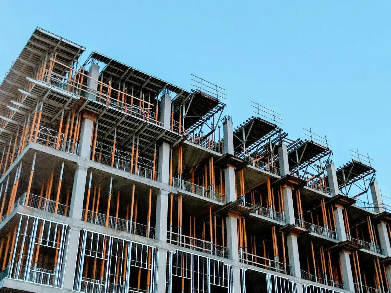 Budowa wielopiętrowego budynku z betonowymi słupami i drewnianymi podporami.