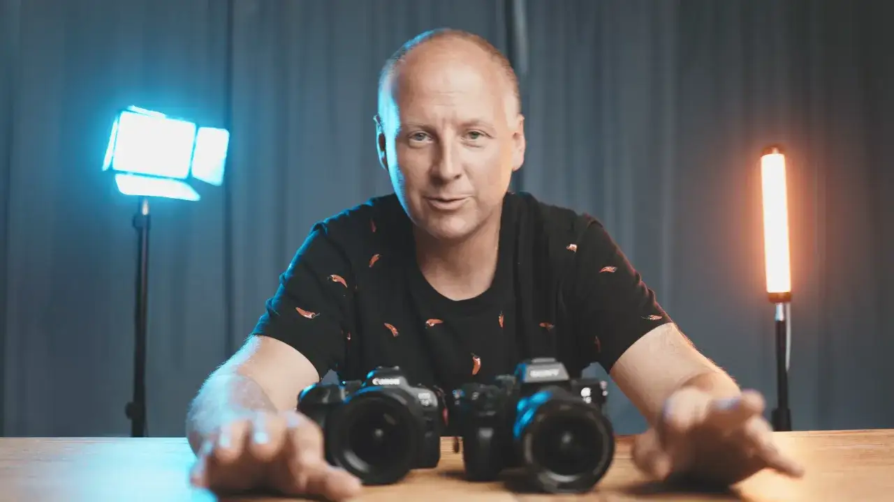 Mężczyzna z aparatami przed sobą, gotowy do rozpoczęcia kursu fotografii.