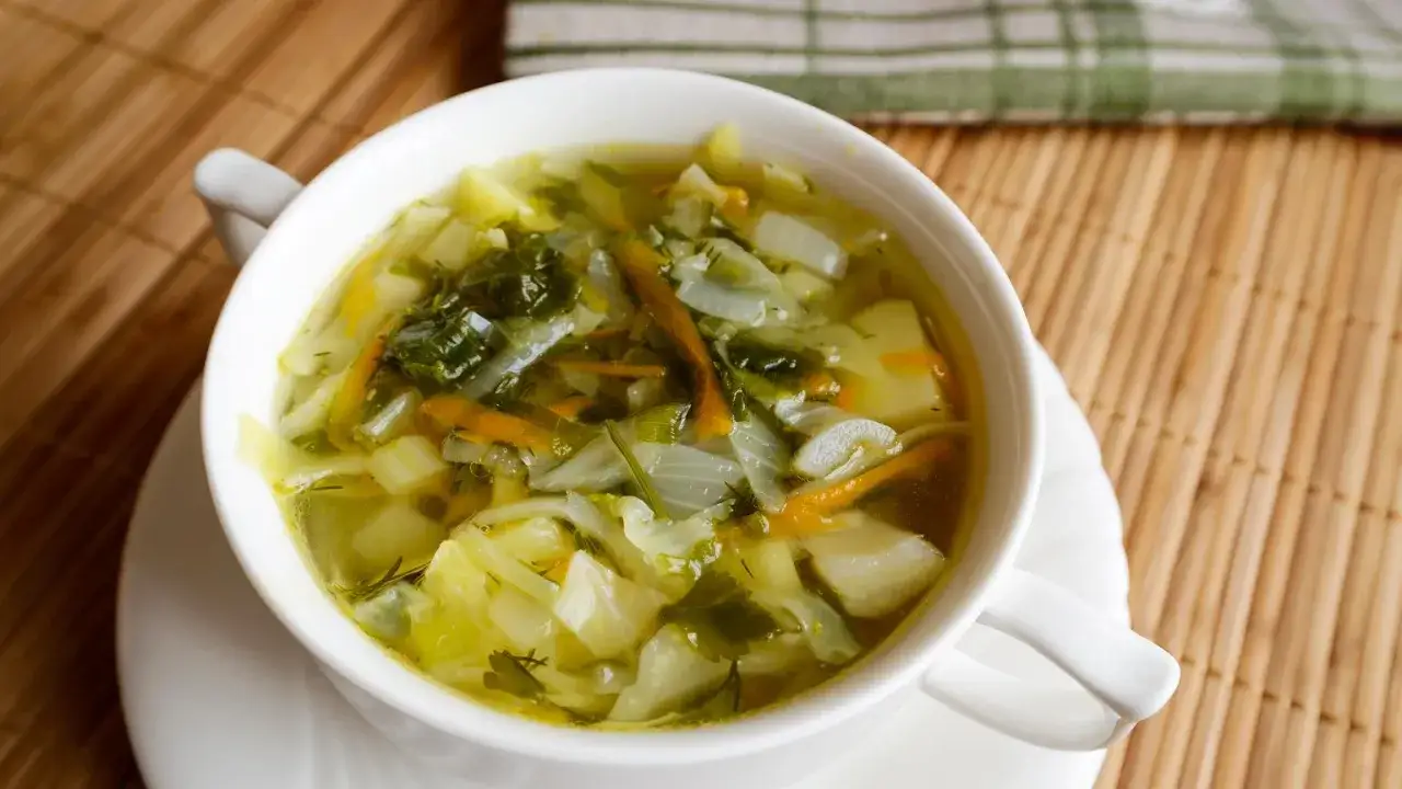 Aromaticzny kapuśniak z młodej kapusty, pełen warzyw i ziół, podany w białej miseczce.