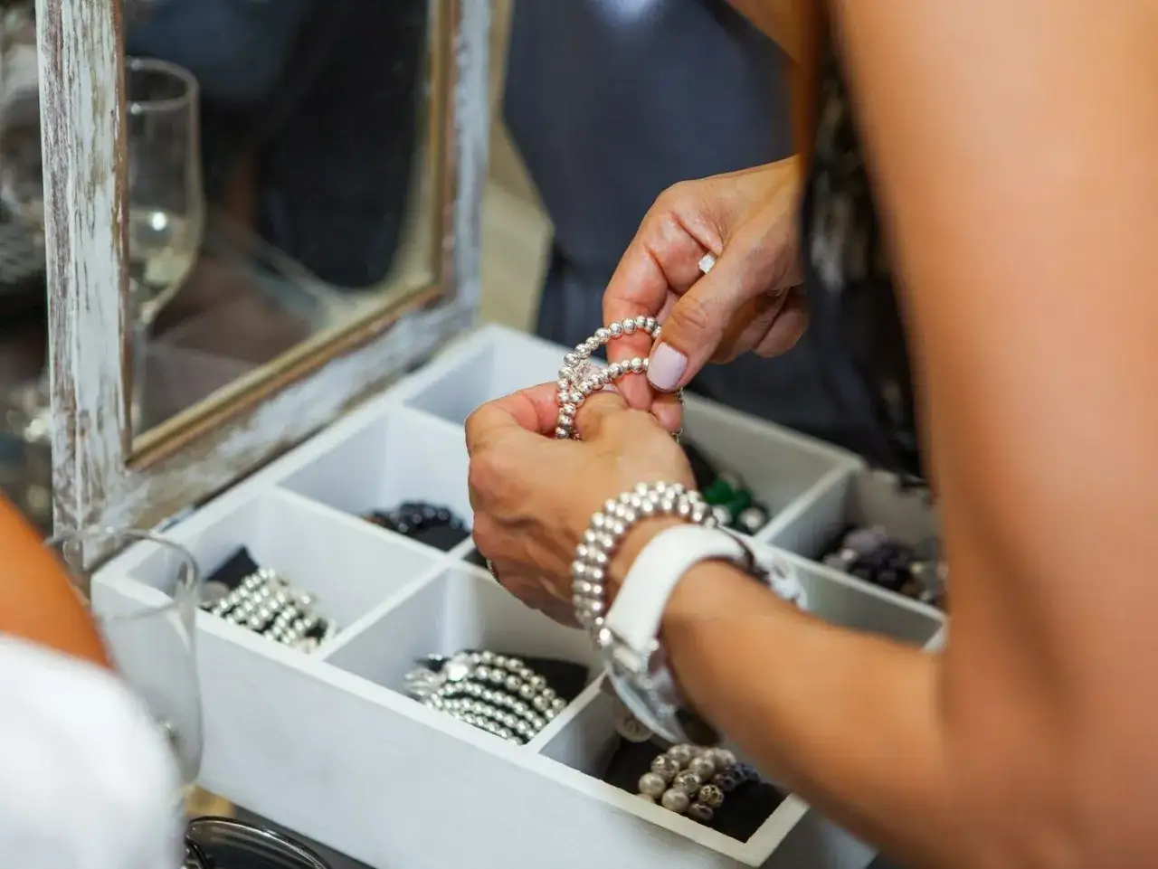 Kobieta układa bransoletki w białym organizerze na biżuterię.