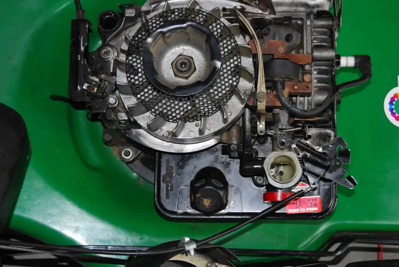 Silnik kosiarki Briggs & Stratton z widocznym gaźnikiem i świecą zapłonową. Podpowiadamy, jak ustawić zapłon w kosiarce Briggs & Stratton.