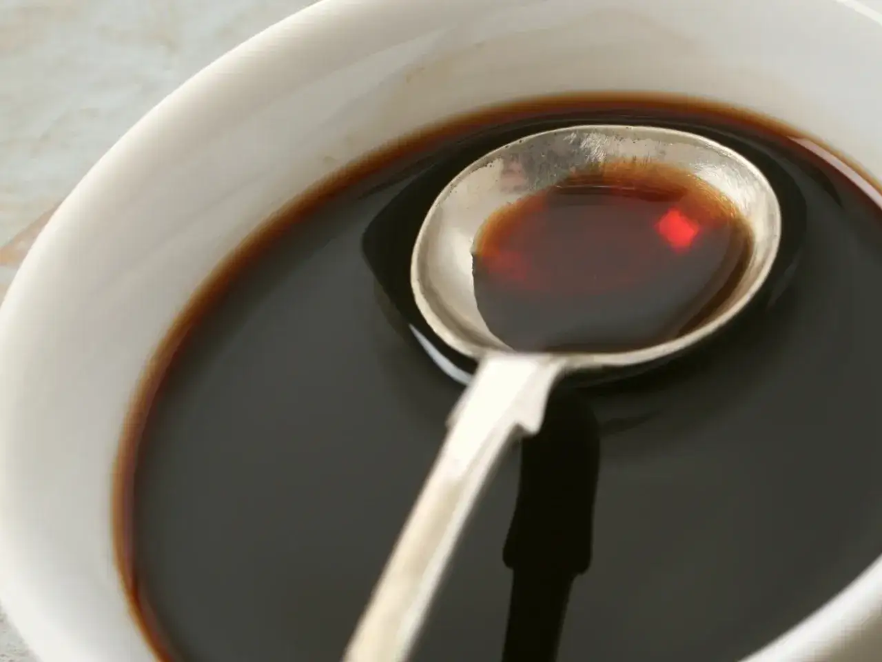 Łyżka z ciemnym płynem, idealnym do sosów i dressingów. Inspiracja do ocet balsamiczny przepisy.