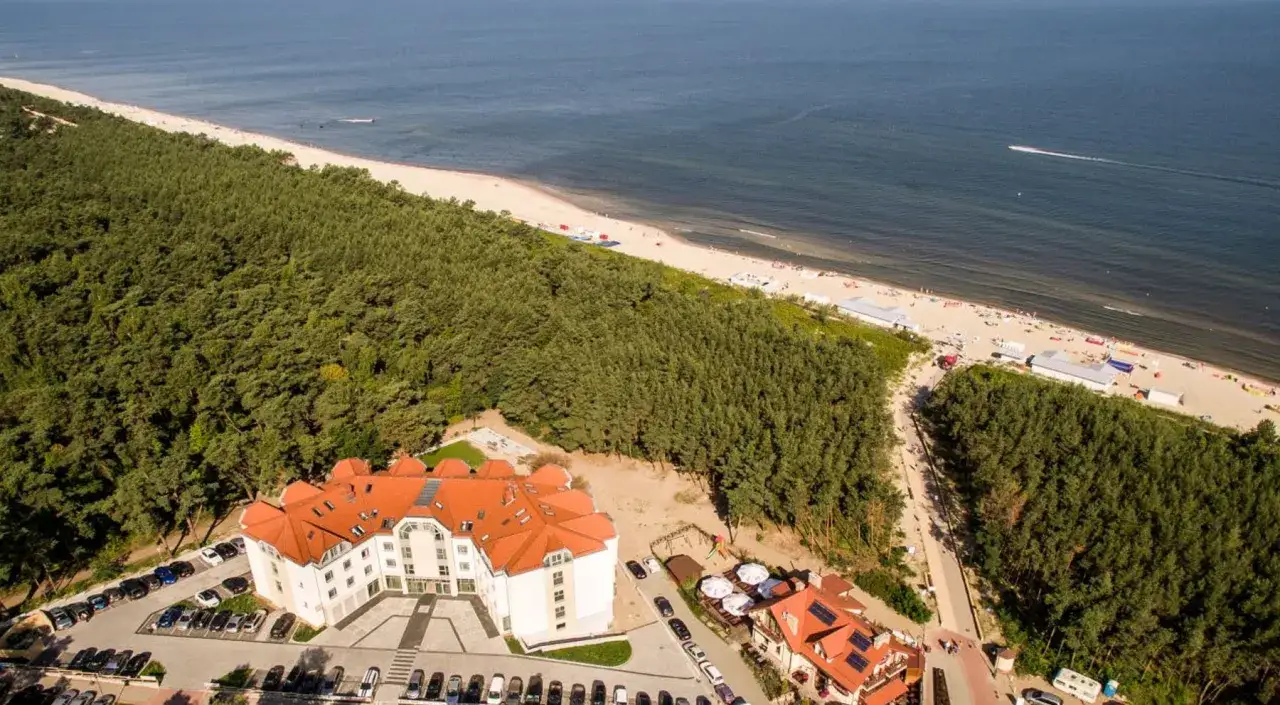 Widok z lotu ptaka na hotel, las i plażę nad Bałtykiem.
