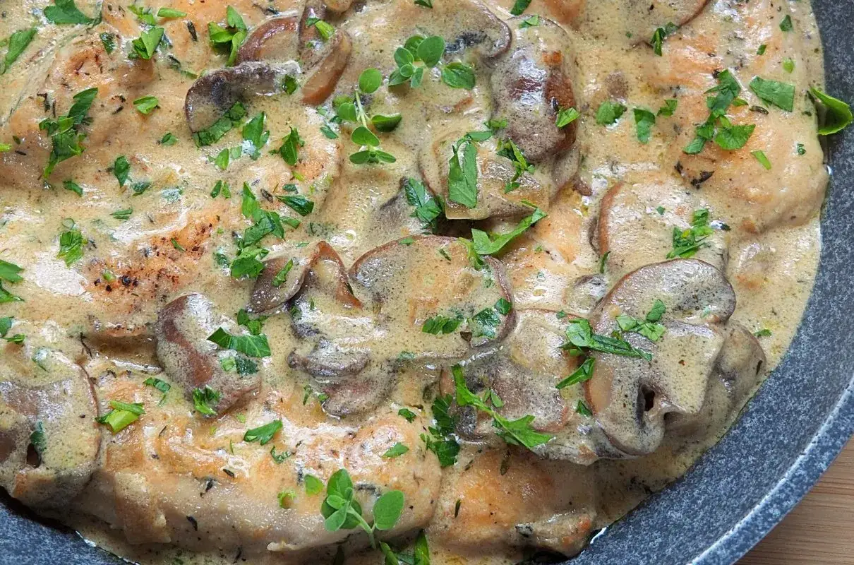 Polędwiczki w sosie pieczarkowym, kremowe i aromatyczne, posypane świeżą natką pietruszki.