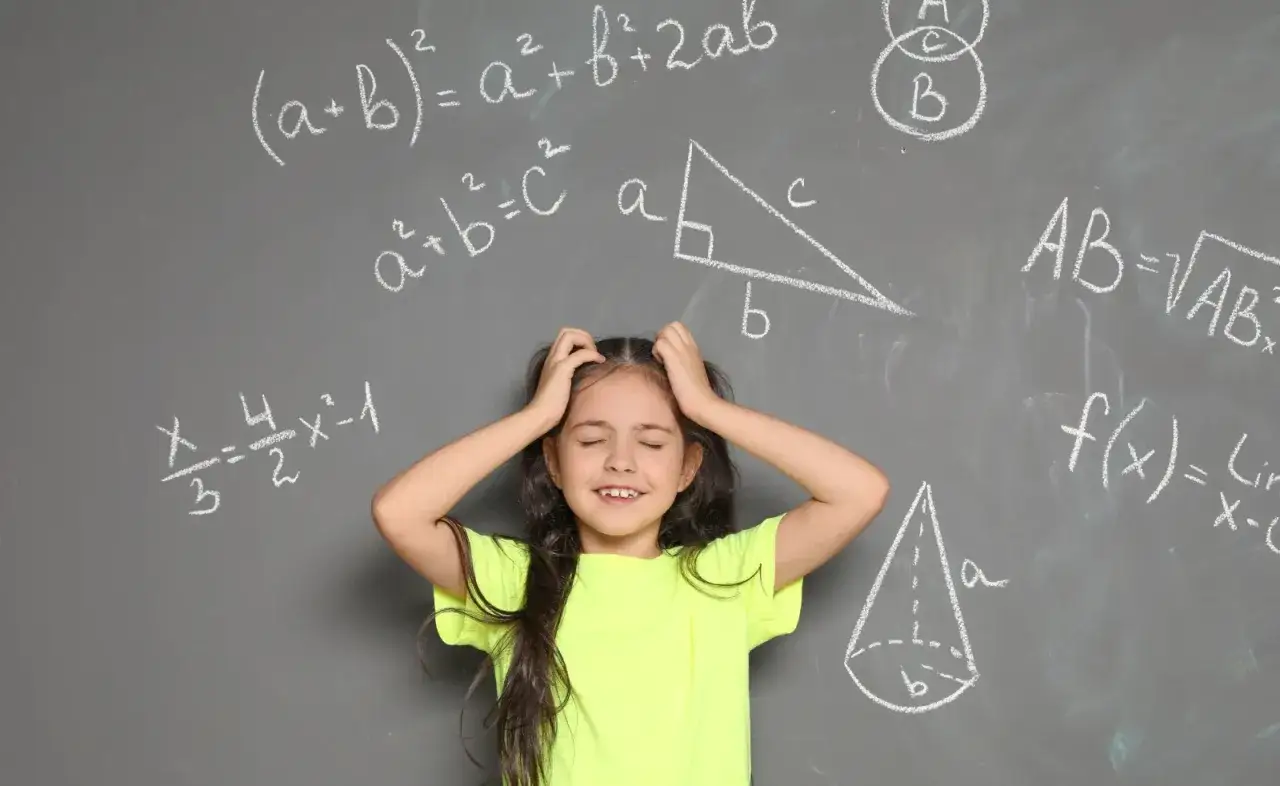 Dziewczynka z rękami wplątanymi we włosy, wyraźnie przeżywająca problemy z matematyką. Wokół niej wzory i figury geometryczne na tablicy.