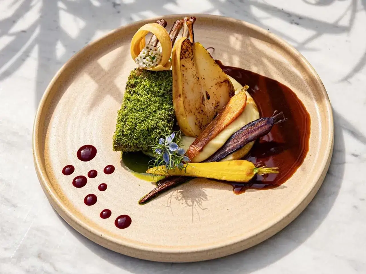 Eleganckie danie z mięsem w zielonej panierce, pieczoną gruszką, kolorowymi marchewkami i sosem.