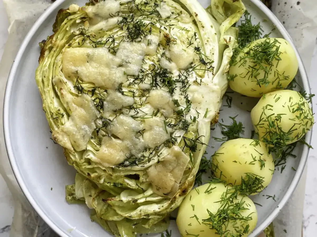 Pieczona młoda kapusta z serem i koperkiem, podana z młodymi ziemniakami. Idealny pomysł, co zrobić z młodej kapusty na obiad.