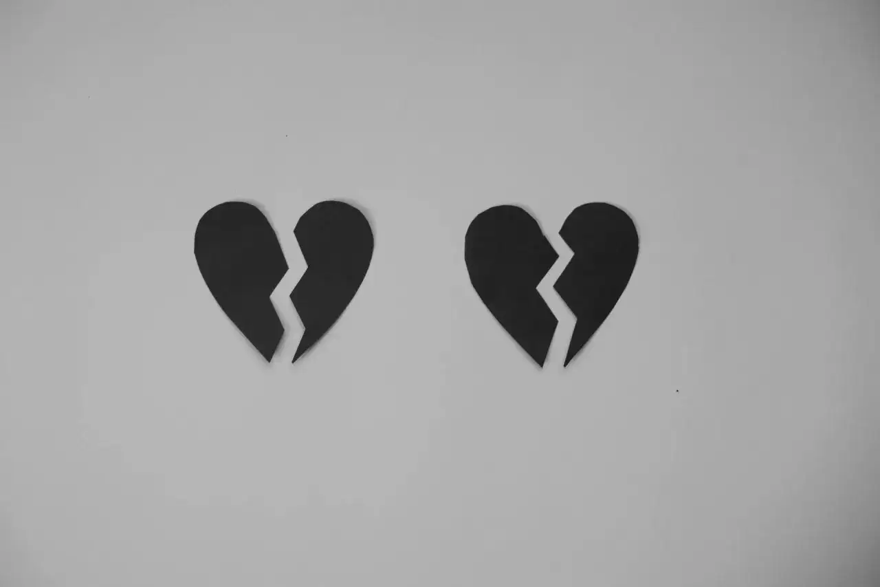 Dwa czarne, pęknięte serca na szarym tle. Symbolizują trudną decyzję, jak zakończyć długoletni związek.